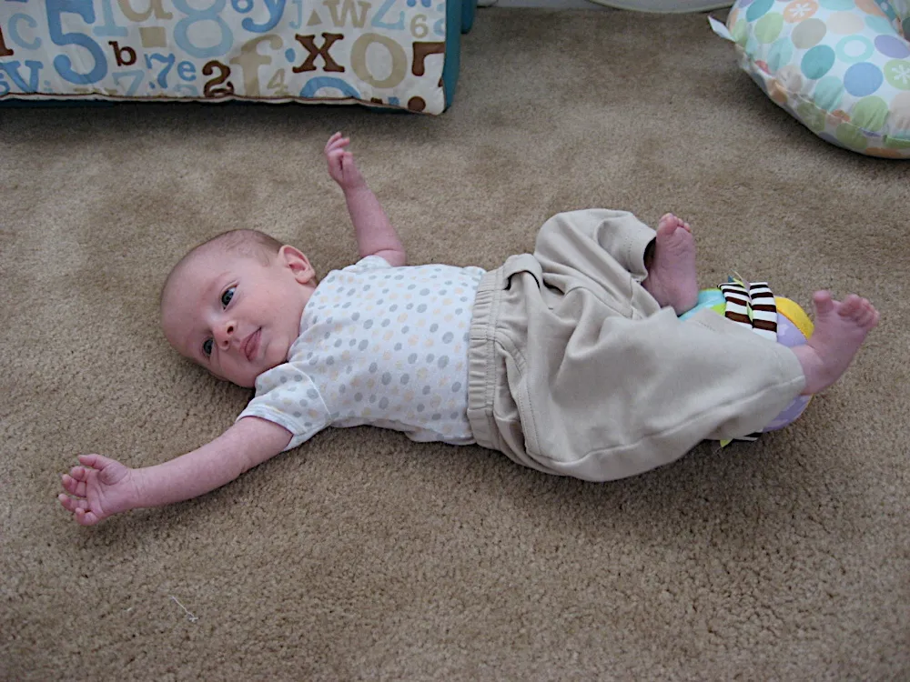 Sprawled on the carpet in a starfish pose, arms and legs flung out, wearing a polka-dot shirt.