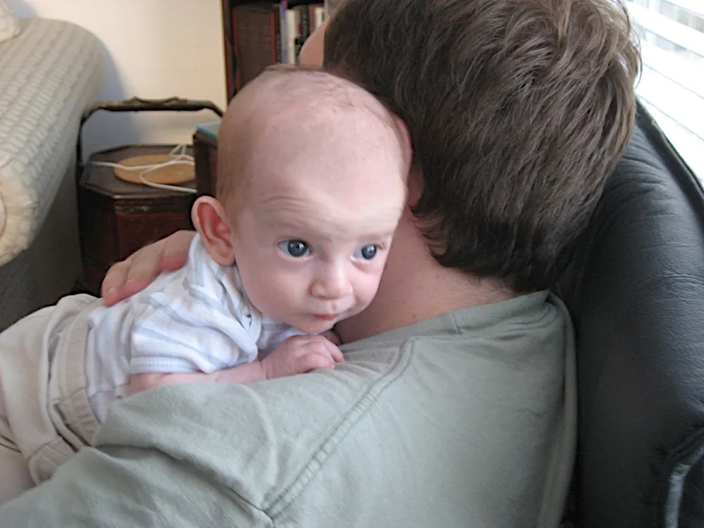 A closer view over the man's shoulder, wide-eyed and puckering his lips.