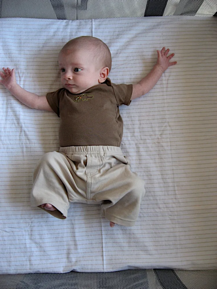 Arms spread wide with one leg drawn up in a frog-like pose, looking to the side.