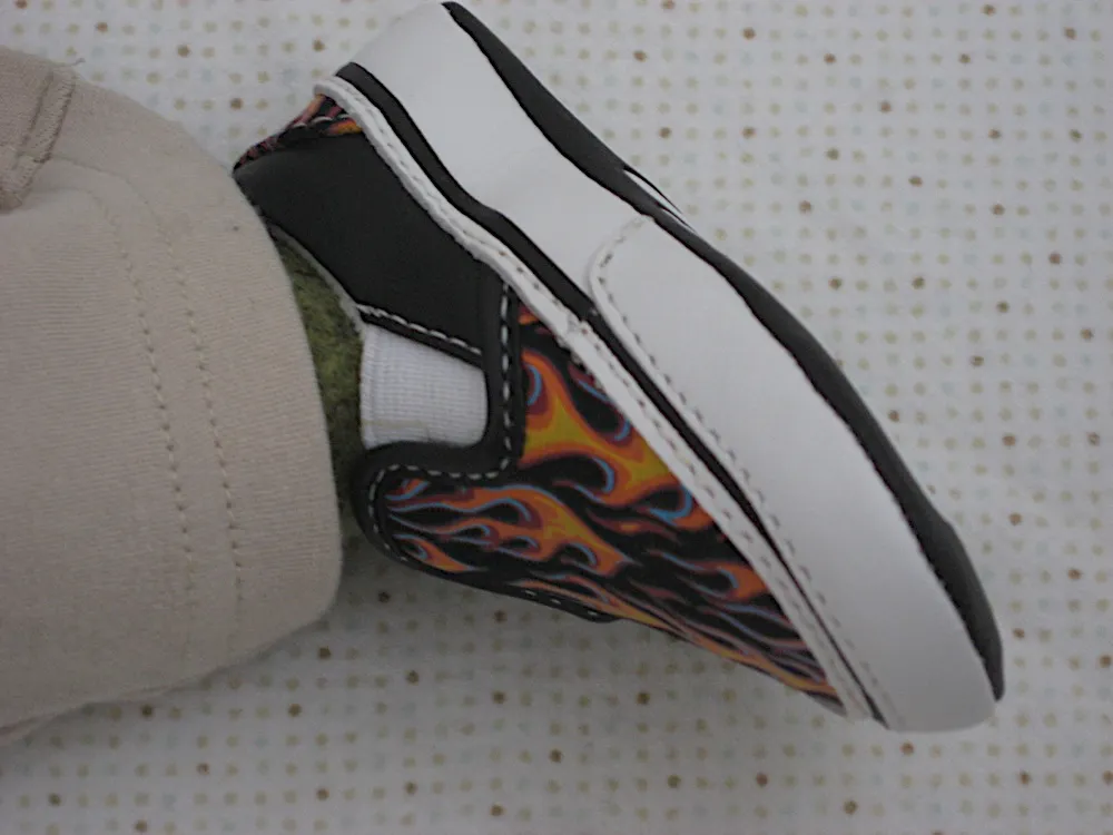 Close-up of one foot in a black and white sneaker with a colorful flame print.